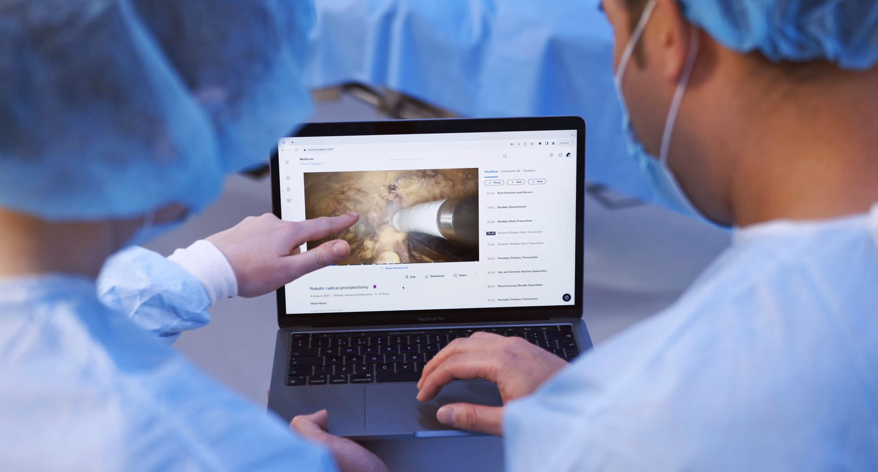 A consultant and a trainee surgeon, both in scrubs, reviewing a Touch Surgery video together on a laptop in theatre